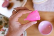Eine Frau hält eine Menstruationstasse zwischen ihren Fingern Eine Frau hält eine Menstruationstasse zwischen ihren Fingern.